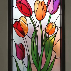 Puede incluir: Una ventana de vitrales con un ramo de tulipanes de colores. Los tulipanes son rojos, naranjas, amarillos, rosas y morados. Los tallos son verdes y el fondo es azul claro.