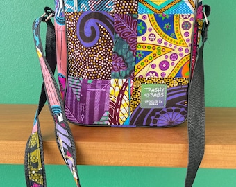 Può includere: Una borsa a tracolla in patchwork colorata con una tracolla regolabile nera. La borsa ha una tasca con cerniera sul davanti e un'etichetta che recita "Trashy Bags - Riciclato in Ghana".