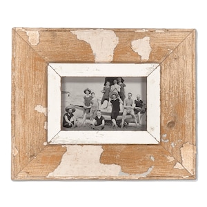 May include: A rectangular photo frame with a distressed, weathered look. The frame has a light brown wood exterior with white inner trim. The black and white photo shows a group of people on a beach. The frame is perfect for displaying vintage photos.