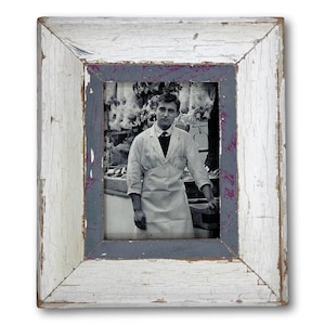 May include: A vintage framed photograph featuring a black and white image of a man in a butcher shop. The frame is rectangular with a distressed, white painted finish, accented with gray and purple trim.