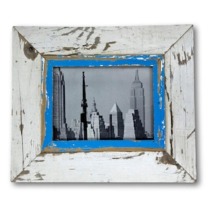 May include: A rectangular picture frame with a black and white image of a city skyline. The frame is made of distressed wood painted white with blue accents. The image features the Empire State Building.