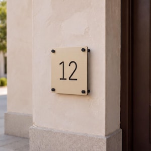 Letrero personalizado con número de casa: placa de HPL mate color arenisca con separadores negros.