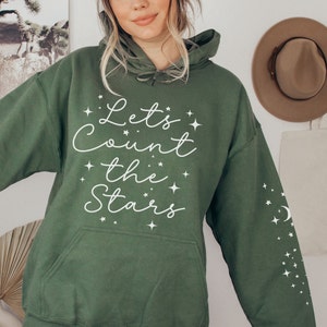May include: A green hooded sweatshirt with the text "Let's Count the Stars" in white cursive lettering and a white crescent moon and stars on the sleeve.