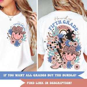 Può includere: Maglietta bianca con un design grafico di un viso sorridente che indossa un cappello da cowboy con una fascia a stampa leopardata. La grafica include anche un arcobaleno, cactus e un ferro di cavallo. Il testo "Howdy Fifth Grade" è scritto sulla maglietta.