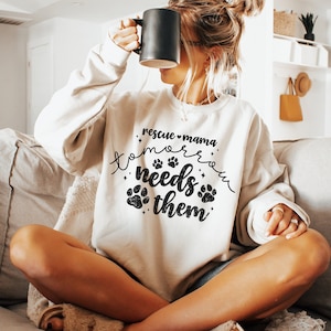 May include: A white sweatshirt with the text "rescue mama tomorrow needs them" in black with paw prints and stars.