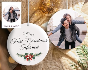 May include: White ceramic Christmas ornament with a photo of a couple and the text "Our First Christmas Married." The ornament has a decorative floral design with red and green accents. A smaller photo is also visible.