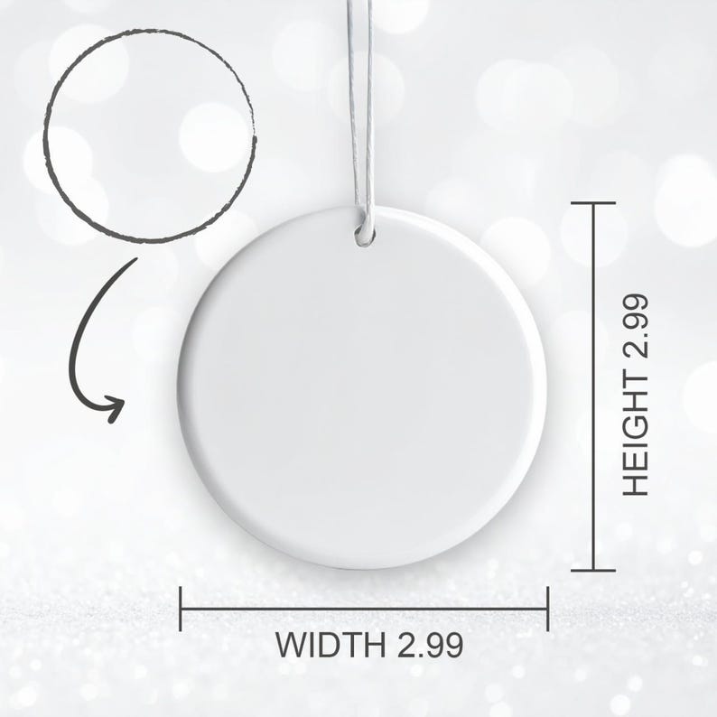 May include: A white, round ornament with a string for hanging. The ornament is 2.99 inches in width and 2.99 inches in height. A black arrow and circle are drawn above the ornament. The background is a soft, blurred white.