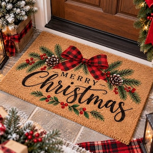 May include: A rectangular tan coir doormat featuring the black script text Merry Christmas. The design includes a large red and black buffalo plaid bow, green pine branches, brown pinecones, and clusters of small red berries as accents.