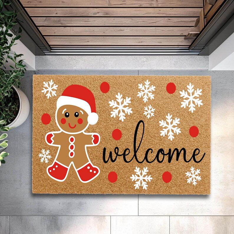 May include: A rectangular doormat featuring a gingerbread man in a Santa hat, snowflakes, and the word "welcome". The mat is brown with red and white details, ideal for the festive period.