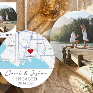 May include: Ornament featuring a photo of a proposal on a pier. A map of Long Beach, CA, with a heart marking the location, and the names "Carol & Joshua" with "ENGAGED 08.14.2026" are also displayed.