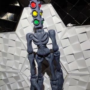 May include: A gray articulated skeleton figure with a traffic light head. The traffic light has red, yellow, and green lights.