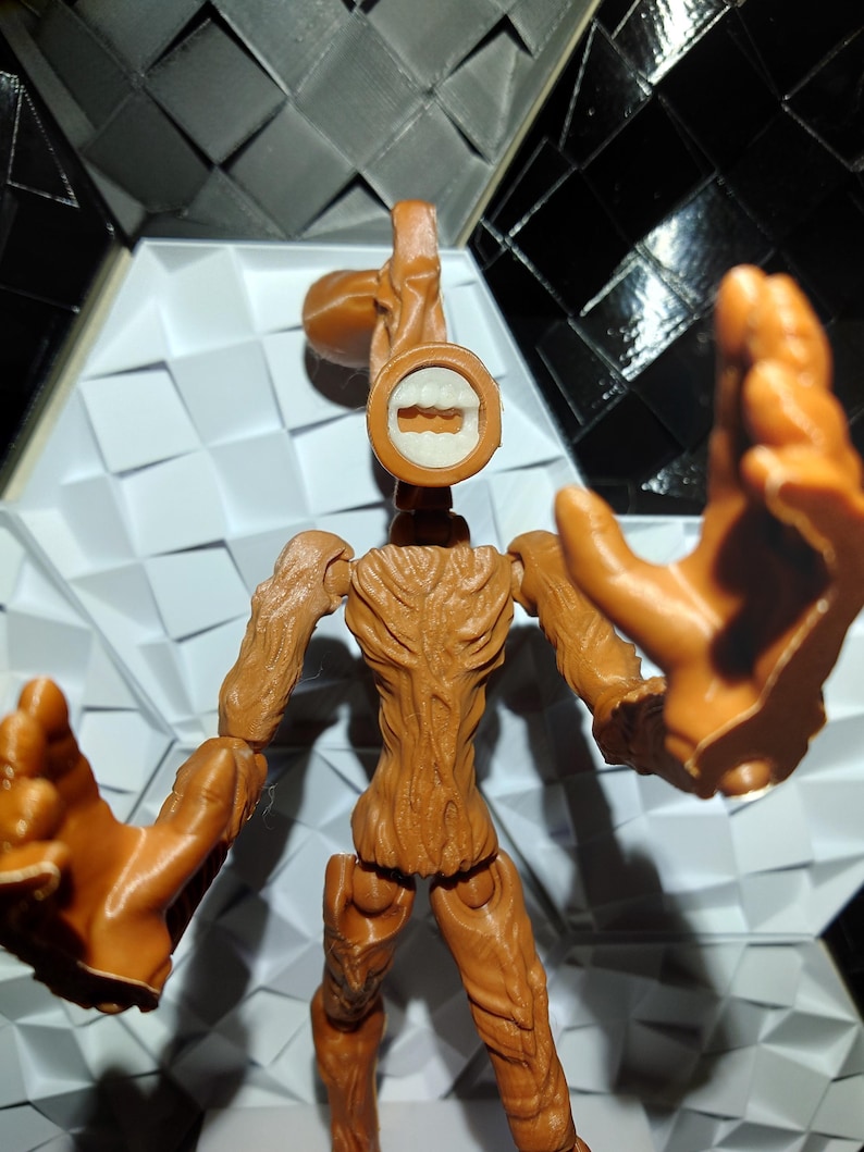 May include: A brown articulated action figure of a creature with a long neck and a toothy grin. The figure has a textured, tree-like body and is posed with its arms outstretched.