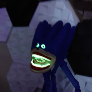May include: A blue, monster-like figure with glowing green eyes and a wide, open mouth revealing glowing teeth. The figure has long, thin legs and a textured head. The background features geometric shapes.