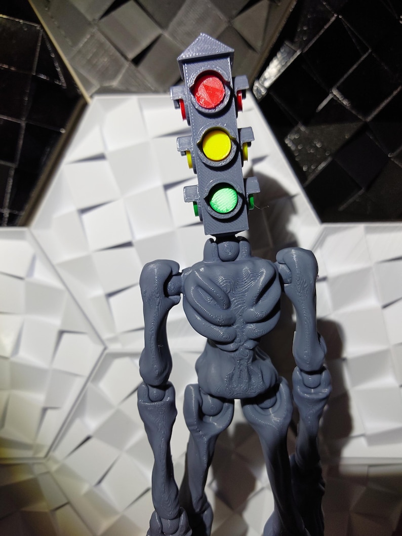 May include: A gray 3D printed figure of a skeleton with a traffic light for a head. The traffic light has red, yellow, and green lights.