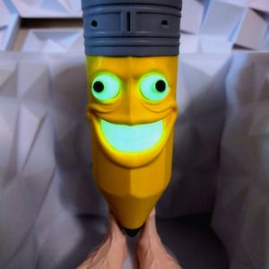 Op de afbeelding: Een grillige gele potloodvormige figuur met een rode gum en een grijze ferrule. Het potlood heeft een cartoonachtig gezicht met gloeiende groene ogen en een lachende mond. Het potlood heeft twee voeten. De achtergrond is een wit geometrisch patroon.
