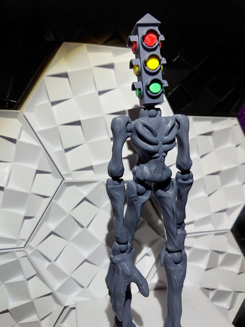 May include: A gray articulated action figure with a traffic light head. The traffic light has red, yellow, and green lights.