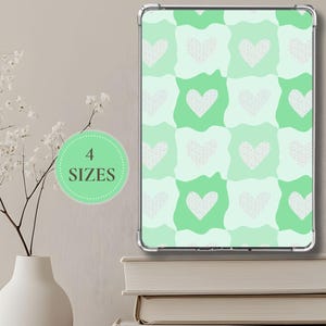 May include: A digital tablet case with a repeating pattern of white dotted hearts on a green and light green background. The text "4 SIZES" is in a green circle. The case is displayed on a stack of books.