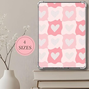 May include: A pink and white patterned tablet case with a heart design. The case is displayed on a stack of books next to a white vase with flowers. A pink circle with the text "4 SIZES" is also visible.