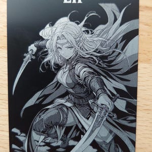 May include: A rectangular black and white game card featuring the text Elf at the top and Token Creature- Elf 1/1 at the bottom. The central illustration depicts a pointed-eared character in armor holding two curved swords in a dynamic pose.