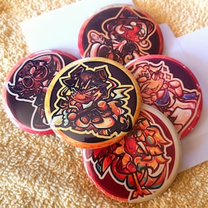 May include: Five colourful round buttons featuring cartoon characters. The buttons depict a pirate, a fox, a wolf, and a dragon, each with unique designs. The buttons are all different colours.