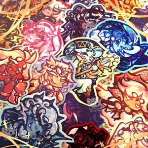 May include: A collection of colorful stickers featuring cartoon characters with various designs. The stickers are printed on glossy paper and have a vibrant, whimsical aesthetic.