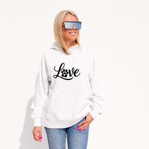 May include: White hoodie with a front pocket and the word "Love" in a black script font, with a paw print replacing the "o". The hoodie is paired with blue jeans.
