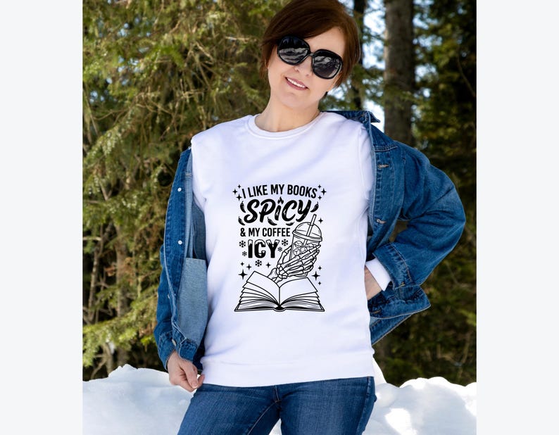 May include: White sweatshirt with the text "I LIKE MY BOOKS SPICY & MY COFFEE ICY". The graphic features a skeleton hand holding a coffee cup over an open book. The person is wearing a denim jacket and sunglasses.