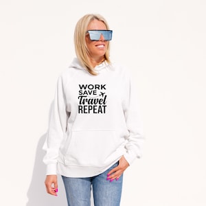 May include: A white hooded sweatshirt with the text "WORK SAVE TRAVEL REPEAT" in black. The sweatshirt has a front pocket and is paired with blue jeans. The image features a person wearing sunglasses.