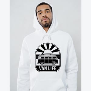 May include: White hoodie featuring a black and white graphic of a van with a surfboard on top, set against a sunburst design. The text "VAN LIFE" is displayed below the van. The hoodie has a drawstring hood.