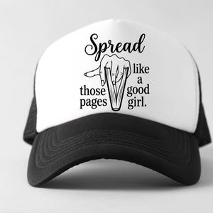 May include: A black and white trucker hat with the text "Spread like those pages like a good girl." The hat has a white front panel and a black brim and mesh back. The graphic shows a hand holding open pages.