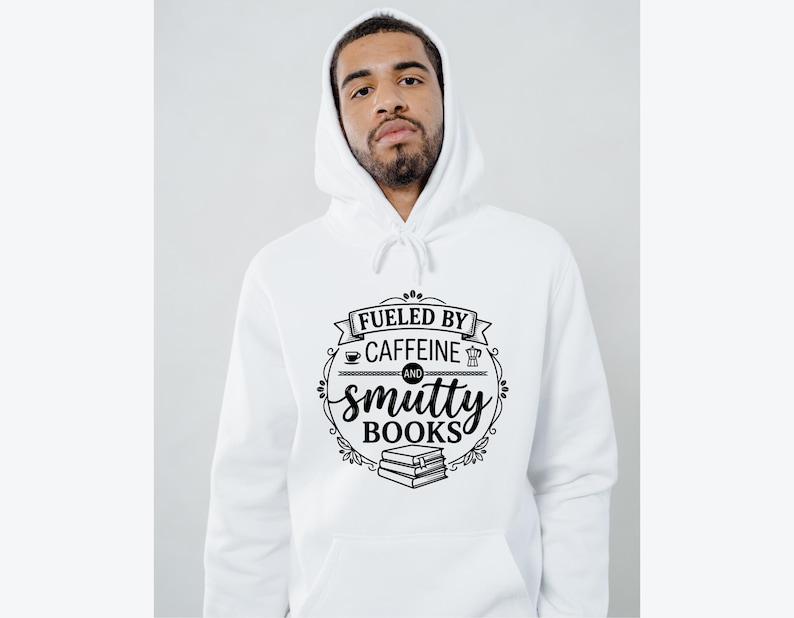 May include: White hoodie with a drawstring and a front pocket. The black graphic reads "Fueled by Caffeine and Smutty Books" with coffee cup, coffee pot, and book illustrations. The hoodie is worn by a person.
