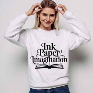 May include: A white ceramic mug with a black handle and the text "But First, Coffee" in a bold, black font. The mug is set against a blurred background, suggesting a cozy setting.