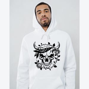 May include: White hooded sweatshirt featuring a black and white graphic of a skull with horns, a bandana, and roses. The design is centered on the front of the hoodie. The hoodie has a drawstring and a kangaroo pocket.