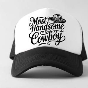 May include: A black and white trucker hat with the text "Most Handsome Cowboy" in a stylish script. The hat features a white front panel with a cowboy hat graphic and a black brim and mesh back.