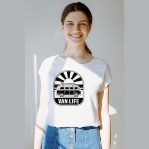 May include: White t-shirt with a black and white graphic of a vintage van, sun, and the words "VAN LIFE". The shirt is made of a soft material and is suitable for casual wear.
