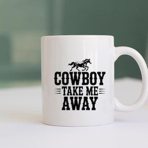 May include: White ceramic mug with a black graphic of a running horse above the words "COWBOY TAKE ME AWAY". The mug has a curved handle and is suitable for hot or cold beverages.