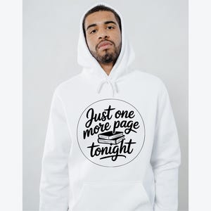 May include: White hooded sweatshirt with the text "Just one more page tonight" in a black circular design. The design includes two stacked books. The sweatshirt has a drawstring hood and a front pocket.