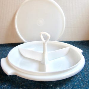 May include: White plastic divided serving dish with a lid and a central handle. The dish has three sections.