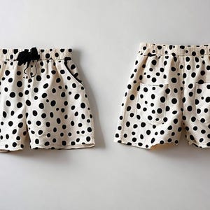 Könnte beinhalten: Eine weiße Shorts mit schwarzen Punkten. Die Shorts hat zwei Taschen auf der Rückseite und einen Kordelzug.