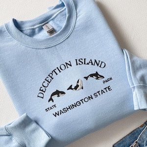 May include: Light blue sweatshirt with a black embroidered design that says "Deception Island State Park Washington State" with three black orca silhouettes.