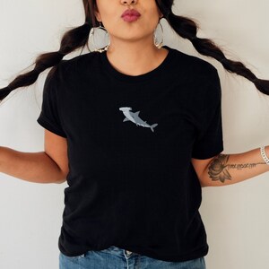 May include: A black t-shirt with a small embroidered hammerhead shark in gray on the front.