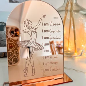 May include: Rose gold mirrored stand with a ballerina silhouette and the text "I am Loved, I am Capable, I am Beautiful, I am Intelligent, I am Kind, I am Patient, I am Happy, I am Callie".