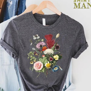 K&ouml;nnte beinhalten: Dunkelgraues T-Shirt mit einem farbenfrohen Blumenstrau&szlig;-Design. Der Strau&szlig; enth&auml;lt rosa, rote, gelbe und wei&szlig;e Blumen mit gr&uuml;nem Laub. Der Text "CUSTOM SHIRTS MANIA" ist in Gr&uuml;n oben rechts aufgedruckt.