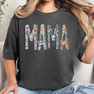 a woman sitting on a couch wearing a t - shirt that says mama