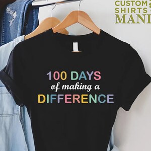May include: Black t-shirt with the text "100 DAYS of making a DIFFERENCE" in rainbow colors.