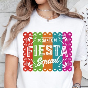 May include: White t-shirt with a colorful graphic of a fiesta banner with the text "SA*TX Fiesta Squad".