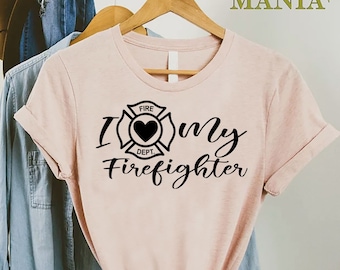May include: A pink t-shirt with a black graphic that says "I love my firefighter" with a firefighter's helmet and heart design.