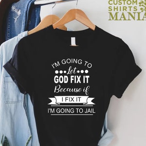 May include: Black t-shirt with white text that reads "I'm going to let... GOD FIX IT because if I FIX IT I'M GOING TO JAIL".