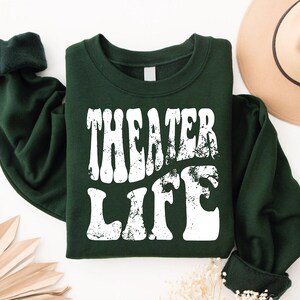 May include: A dark green sweatshirt with the text "Theater Life" in white, distressed lettering.