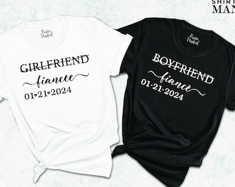 May include: Two white t-shirts with black text. One shirt says "Girlfriend fiancee 01.21.2024" and the other says "Boyfriend fiancee 01.21.2024".